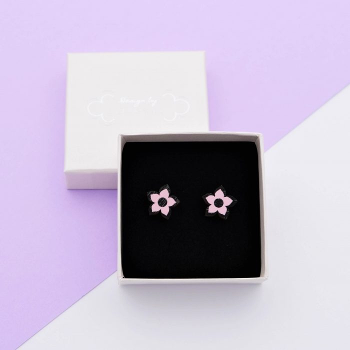 Kesäyö nappikorvakorut, joiden värinä musta ja pinkki. Tappikiinnitys korvaan. Koko: 15 x 15 mm.