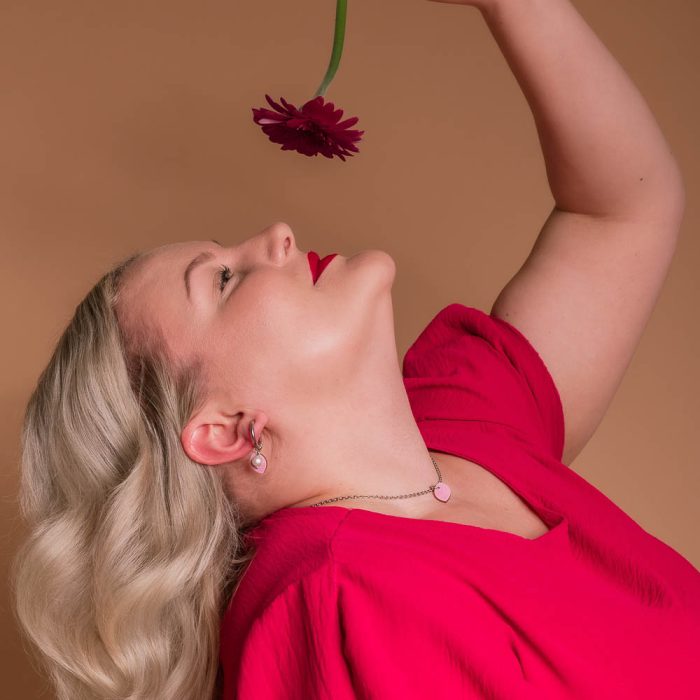 Pinkin ja teräksen väriset Kajo korvakorut ja kaulakoru helmella mallin päällä.